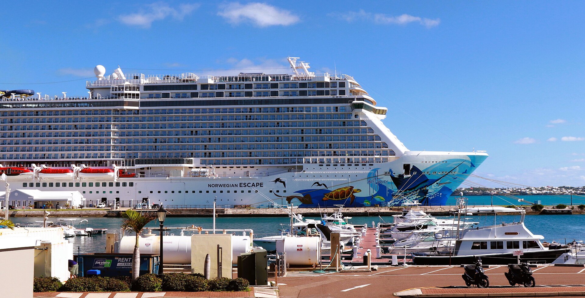 Norwegian Escape berthed at Bermuda's Royal Naval Dockyard with marina boats and turquoise water