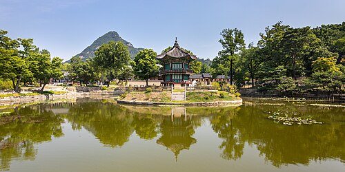 Where to stay for Seoul: Panoramic view of Hyangwonjeong Pavilion in its pond at Gyeongbokgung Palace with blue sky in Seoul