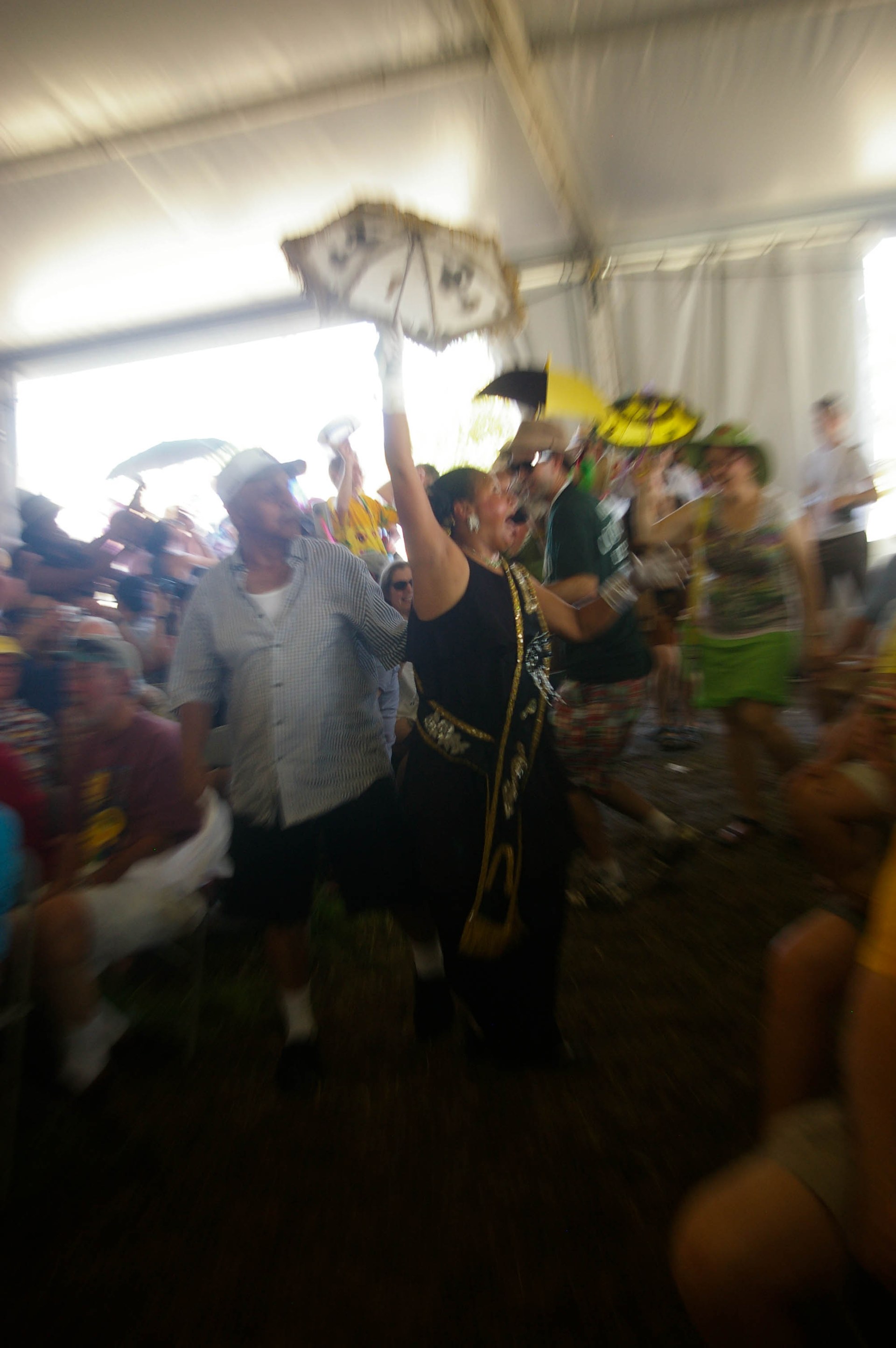 A spirited umbrella parade moving through a crowded New Orleans festival