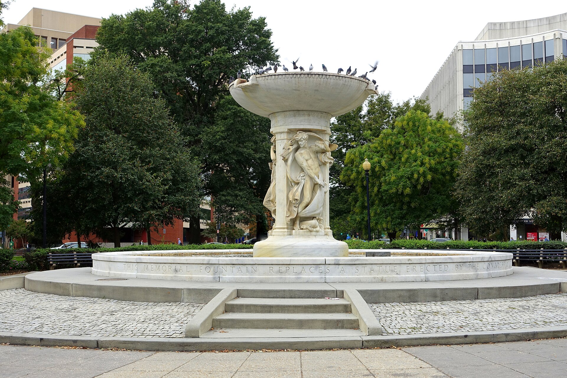 Marble fountain surrounded by trees and city buildings in Dupont Circle