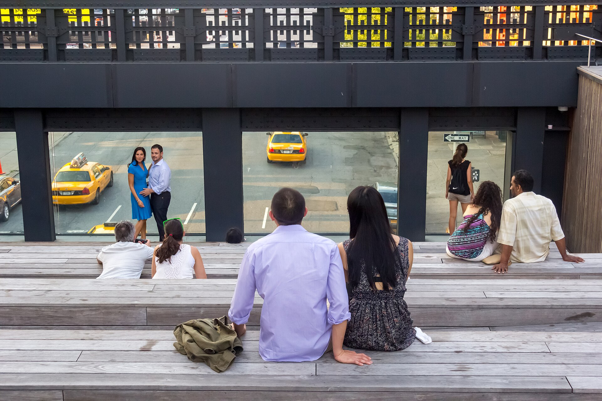 Visitors pausing above yellow taxis on the High Line
