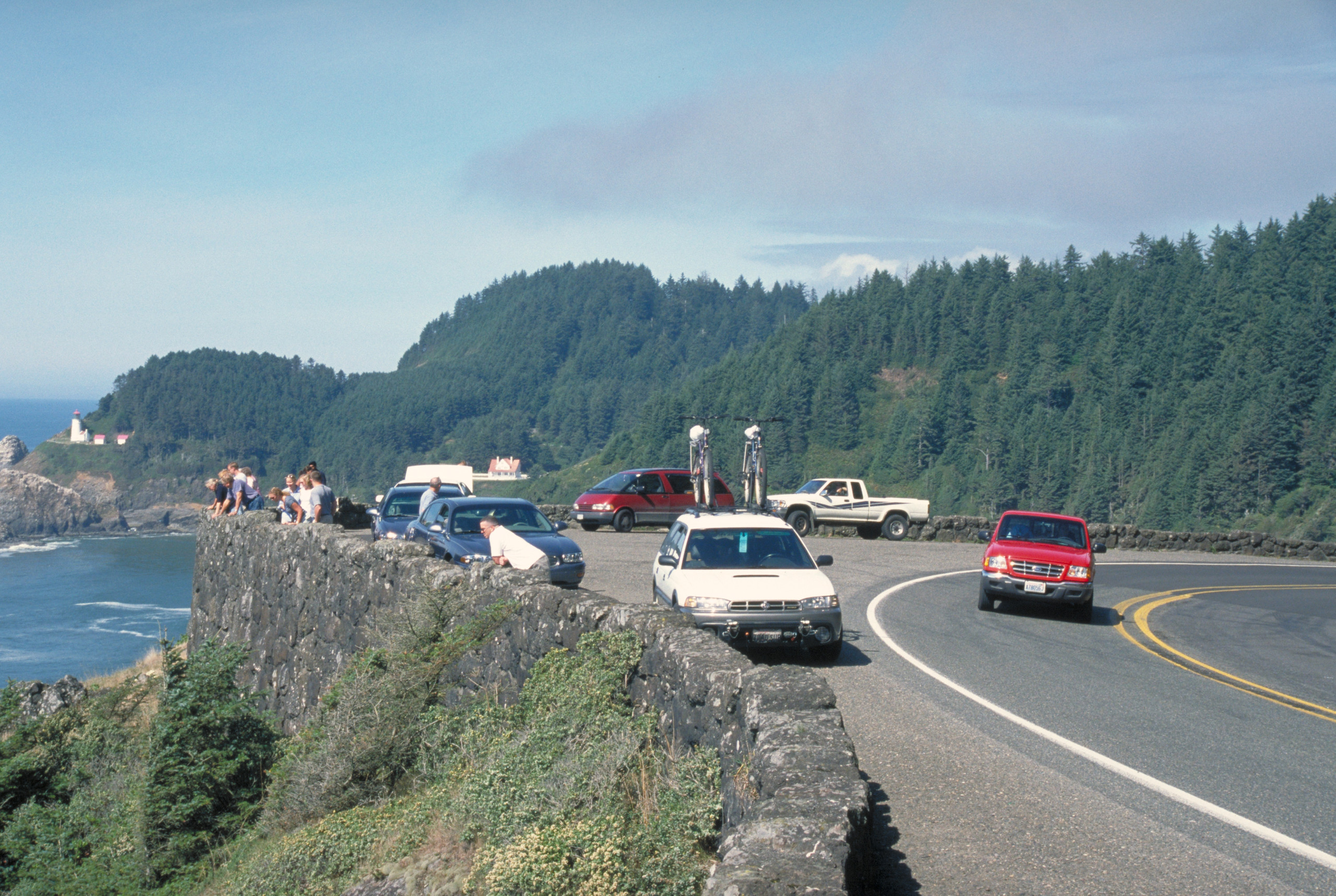 Cars paused at a Pacific Coast Scenic Byway overlook above the Oregon shore