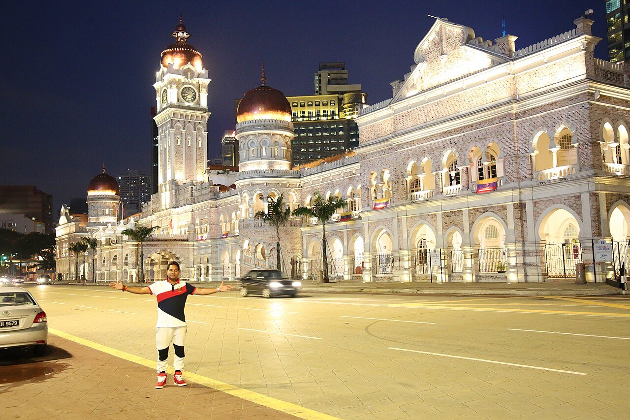 Historic Kuala Lumpur: Sultan Abdul Samad Building in Kuala Lumpur, Malaysia, illuminated at night with a tourist posing in the foreground