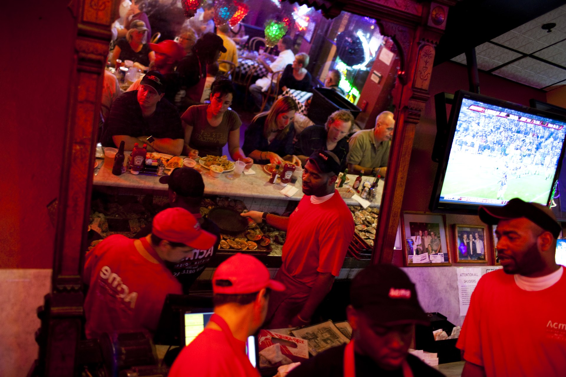 Guests dining and drinking while oyster shuckers work the lively Acme Oyster House bar in New Orleans