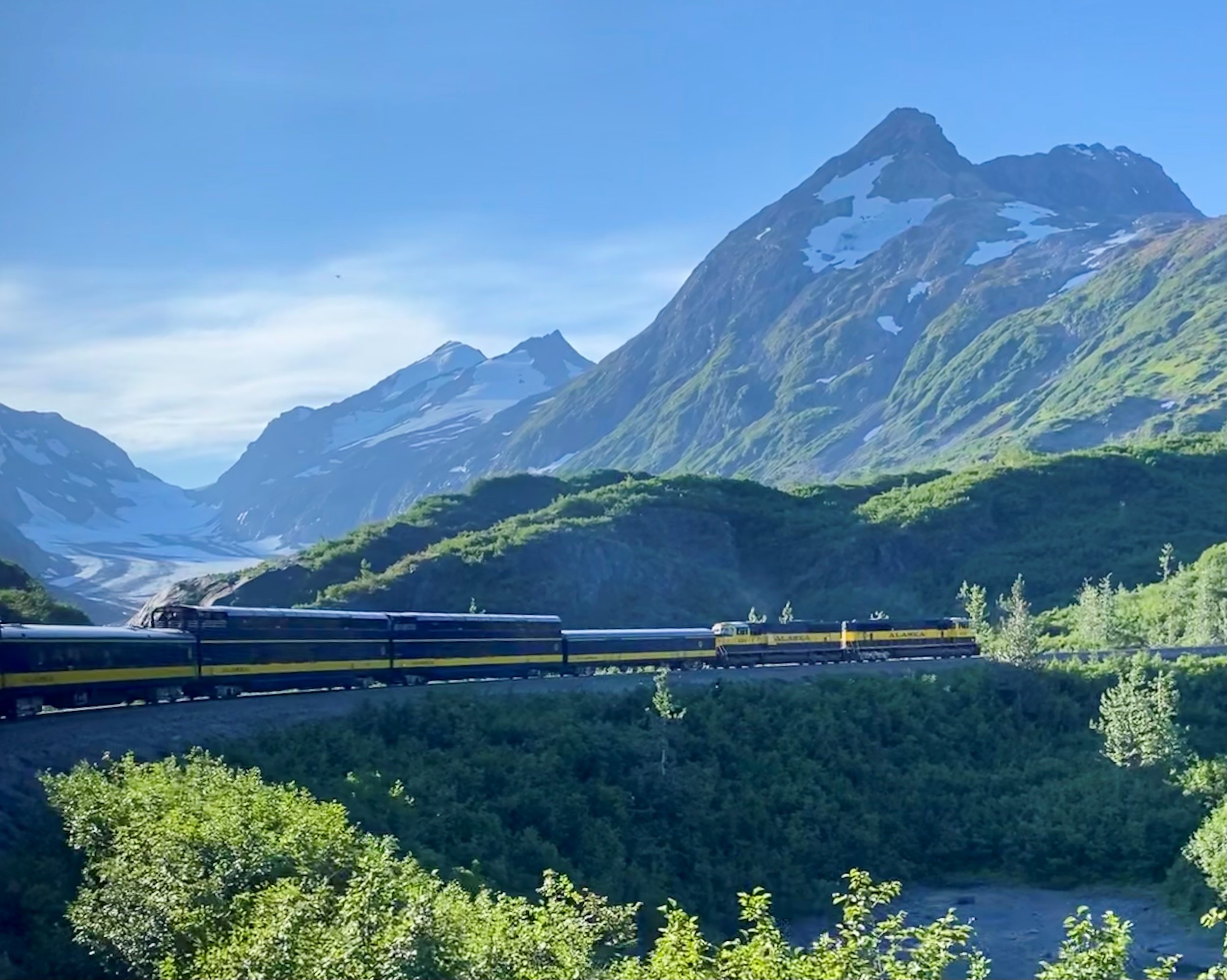 Alaska Railroad Coastal Classic train crossing a mountain valley with Bartlett Glacier beyond