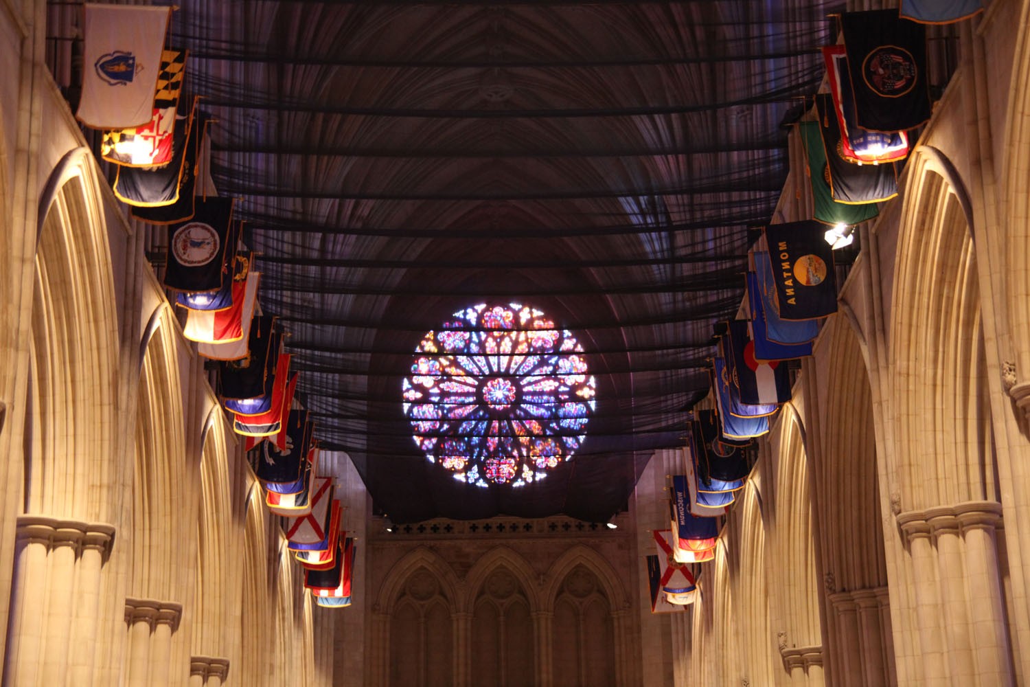 Washington National Cathedral nave framed by state flags and the glowing west rose window