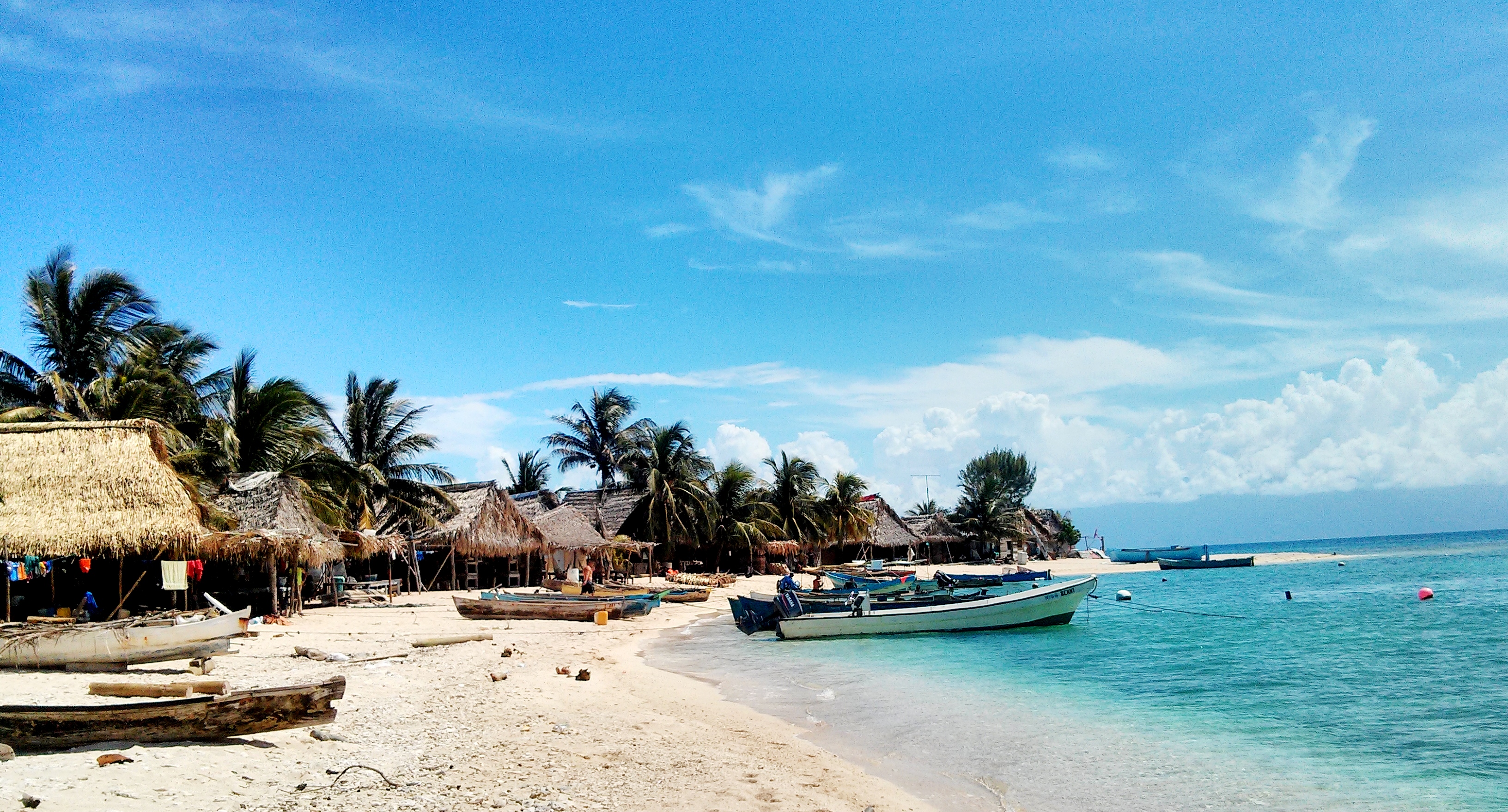 Garífuna community homes, fishing boats, white sand, and turquoise Caribbean water on Chachahuate Cay in Honduras