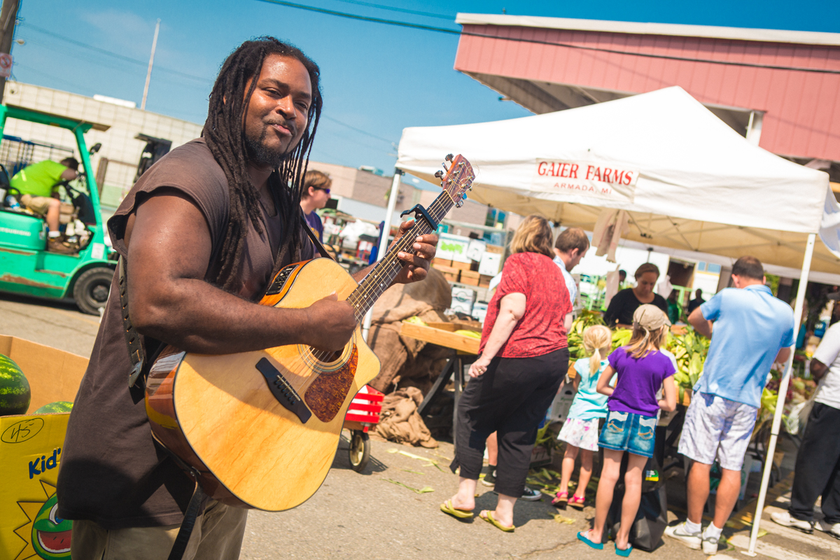 A guitarist performs among shoppers and Michigan farm stands at Detroit's Eastern Market