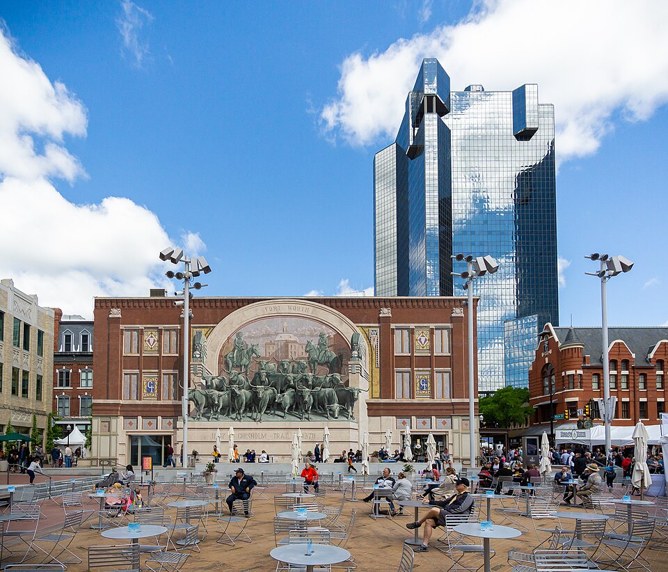 Visitors gather in Fort Worth's Sundance Square before the Chisholm Trail mural and a contemporary glass tower
