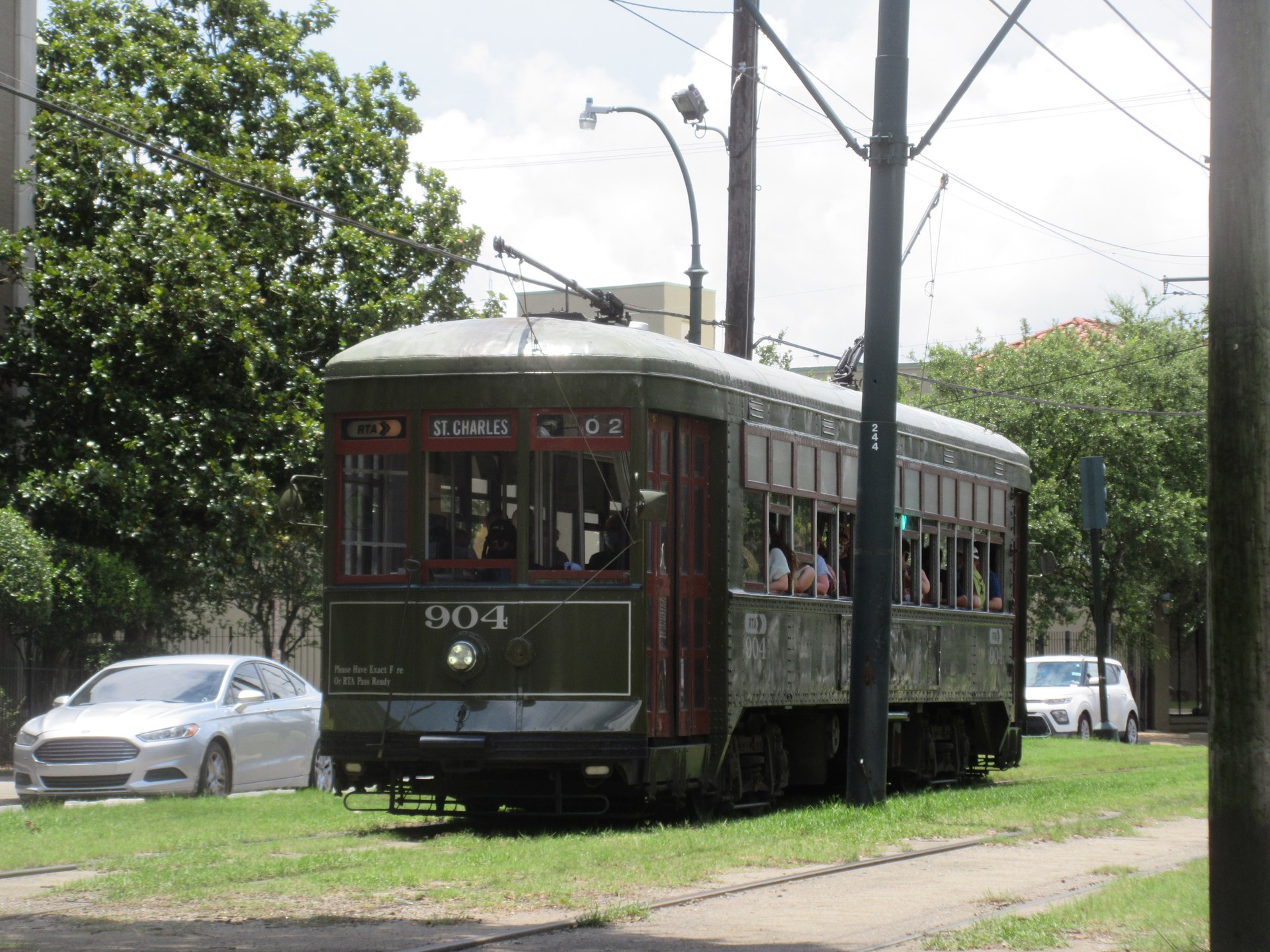 Passengers riding a historic St. Charles streetcar through the leafy Lower Garden District
