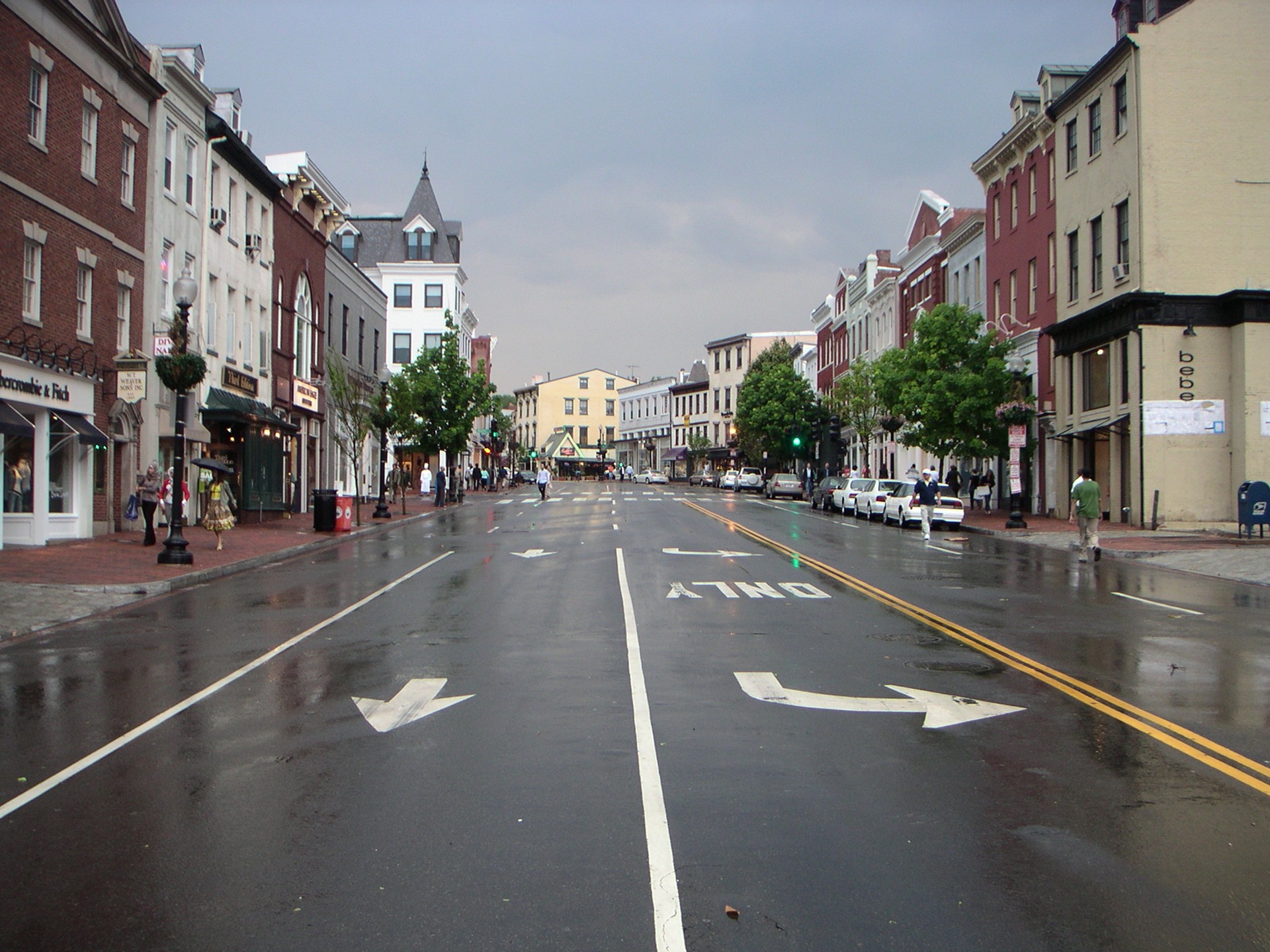Pedestrians browsing historic shops along Wisconsin Avenue in Georgetown after rain