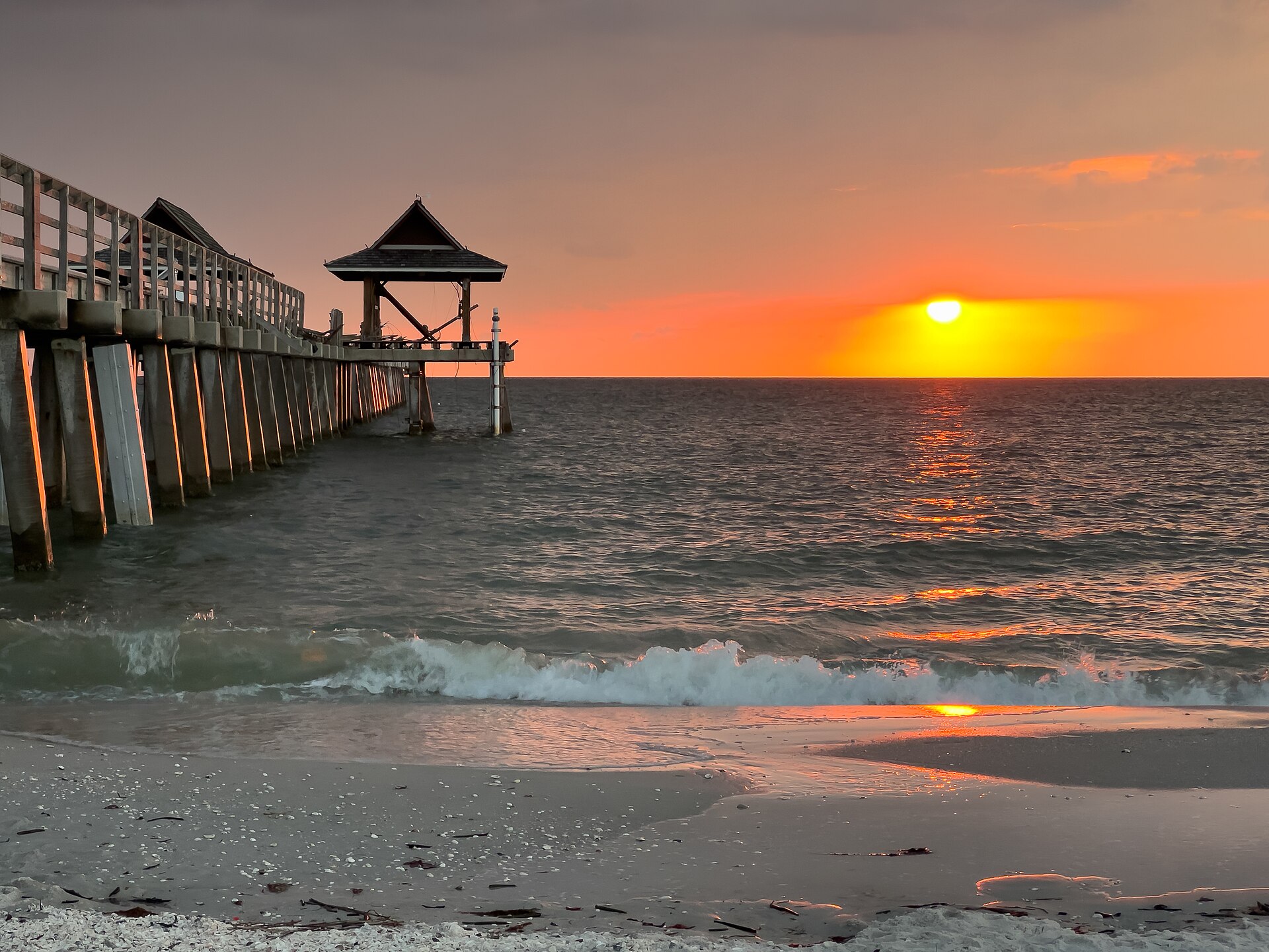 Sunset beside Naples Pier on Florida's Gulf Coast with shells lining the beach