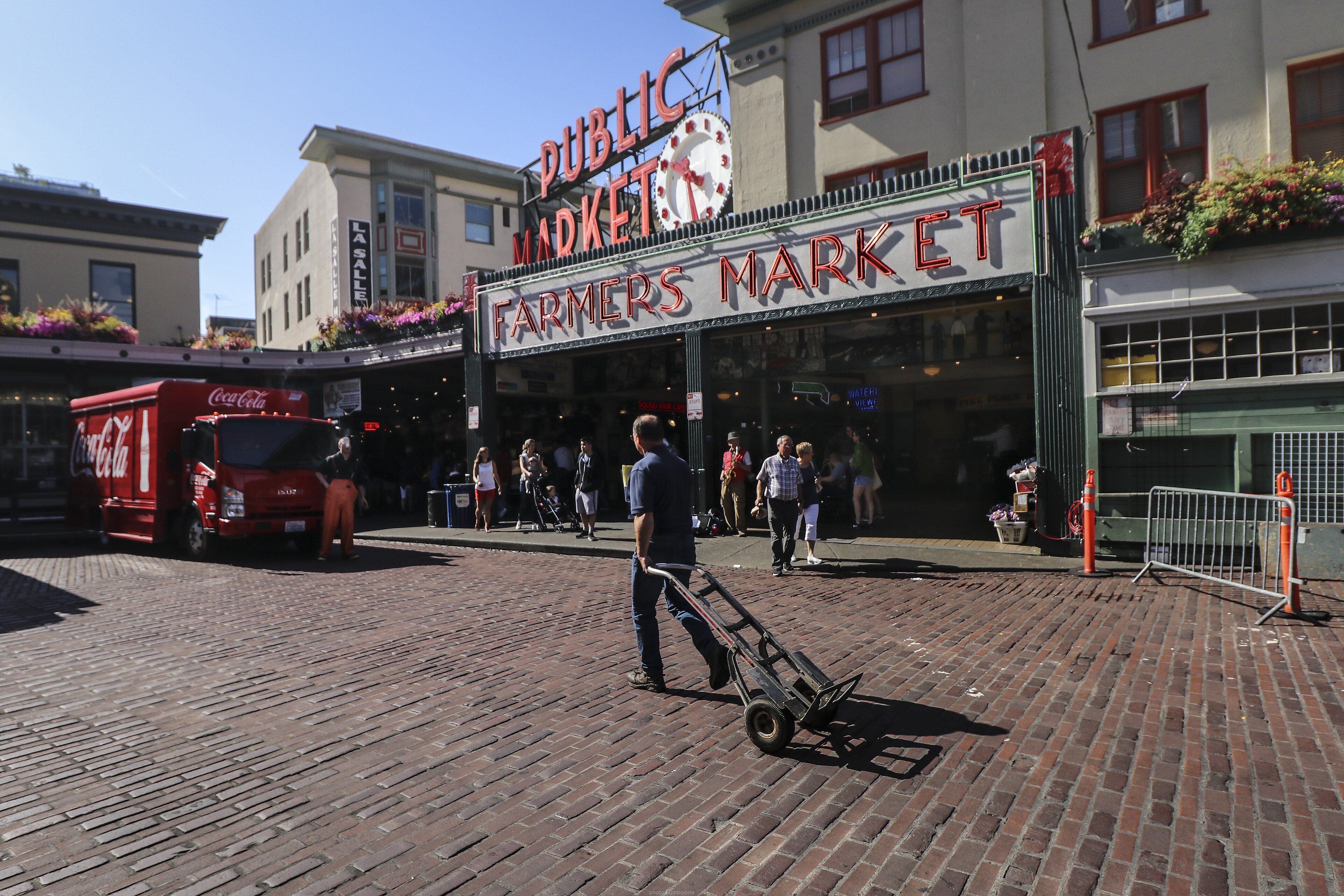 Travelers browsing the fish market beneath the landmark Pike Place Market sign
