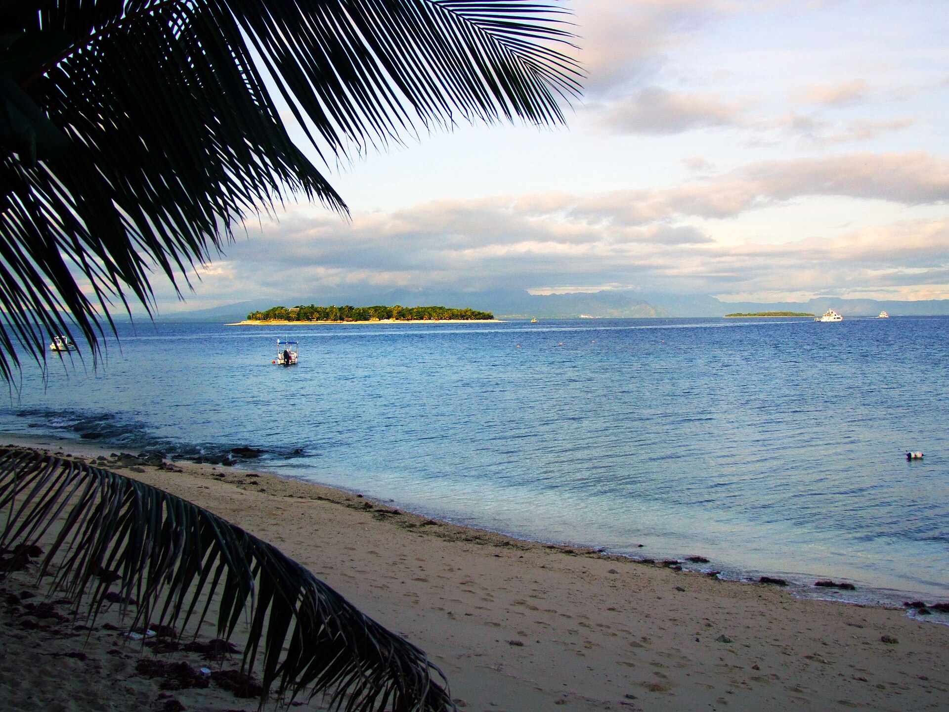 Boats crossing blue water between Beachcomber Island, Treasure Island, and neighboring islands in Fiji's Mamanuca group