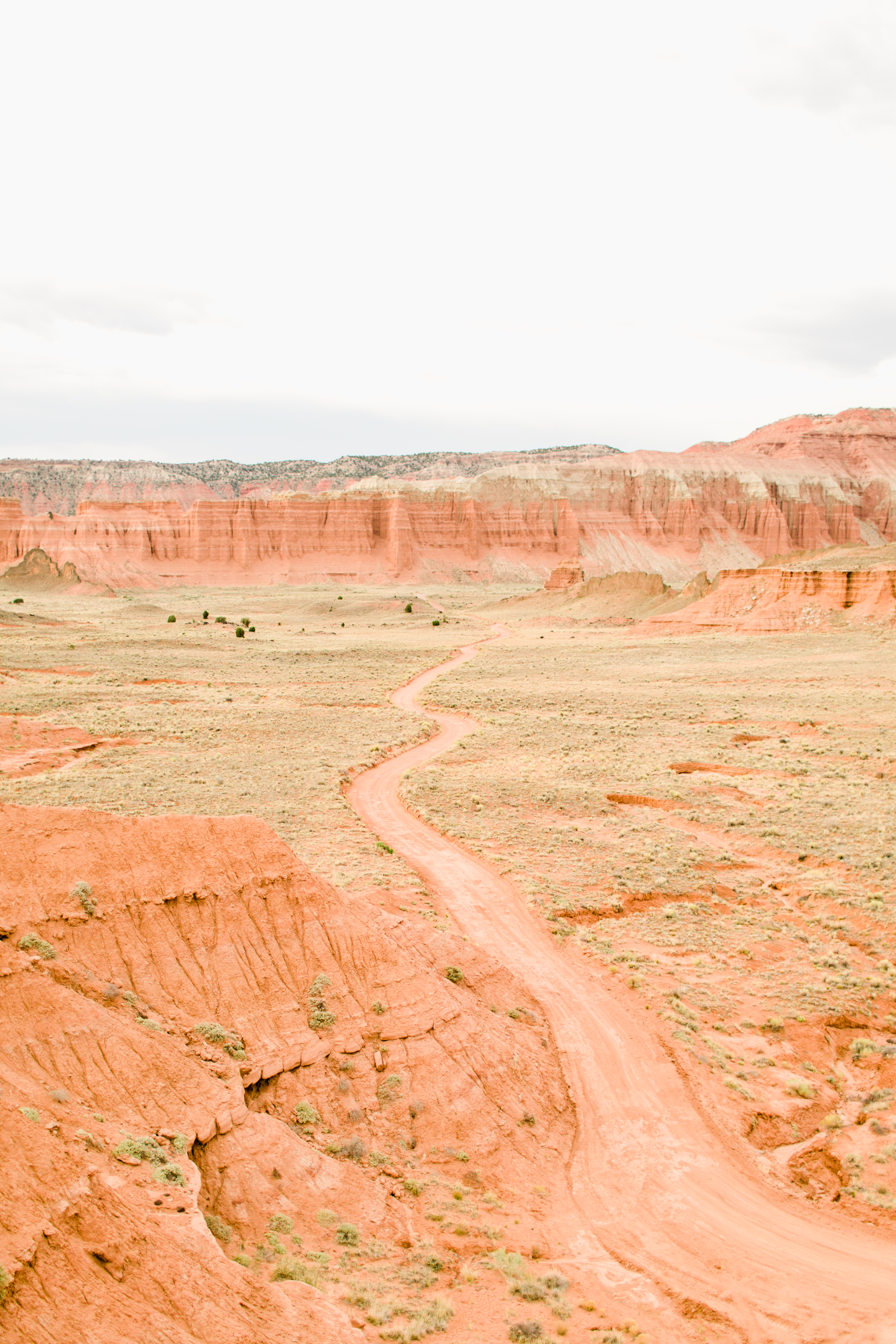 A winding desert road crossing the pale red badlands of Capitol Reef National Park