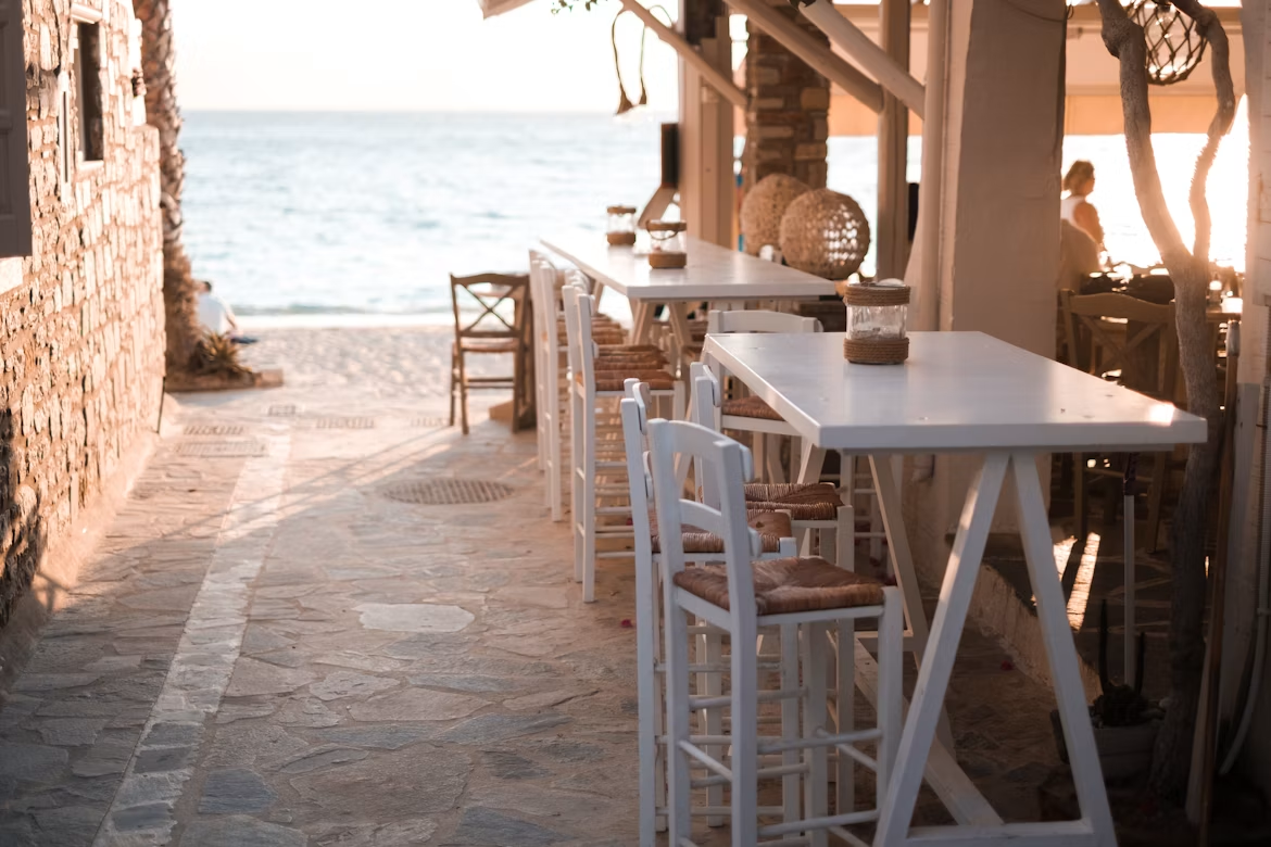 White tables and woven chairs at a seaside taverna in Naxos, Greece