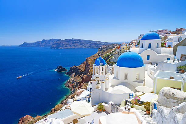 Blue-domed Santorini churches overlooking the Aegean Sea and caldera in Greece