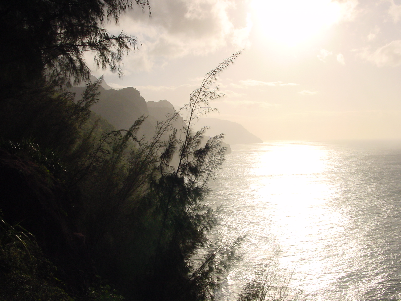 Sunlight crosses the Pacific and the layered sea cliffs of Kauai's Na Pali Coast