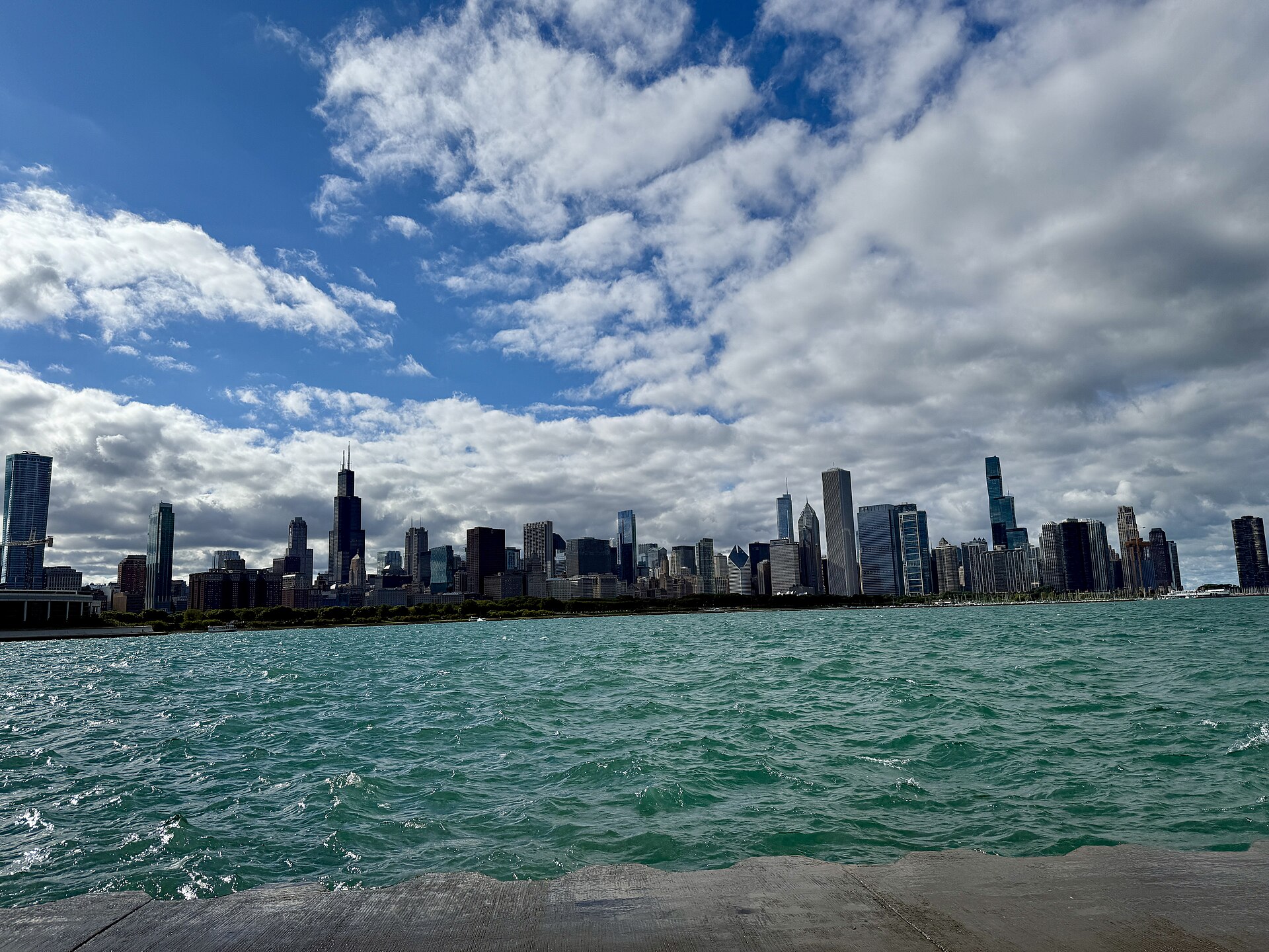 Chicago's skyline rises beyond the blue expanse of Lake Michigan under a dramatic summer sky