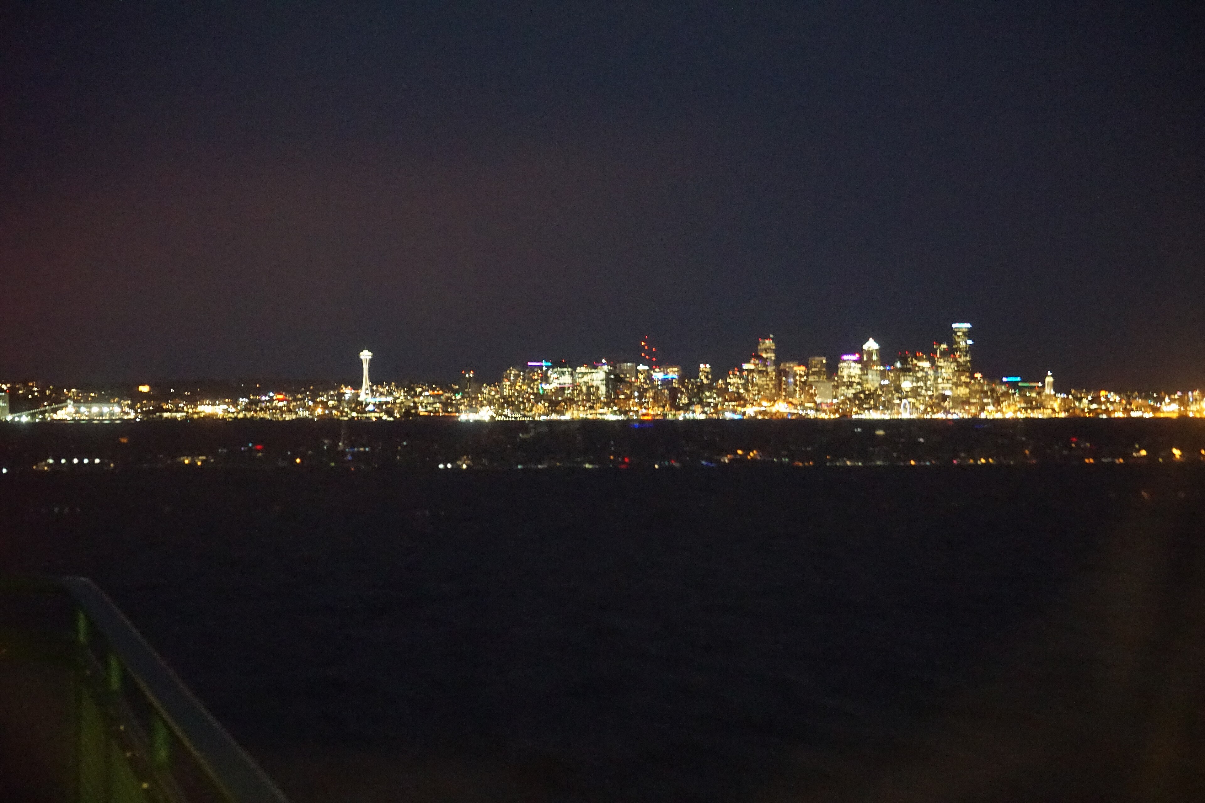 Seattle skyline glowing beyond Puget Sound as seen from a Bainbridge Island ferry