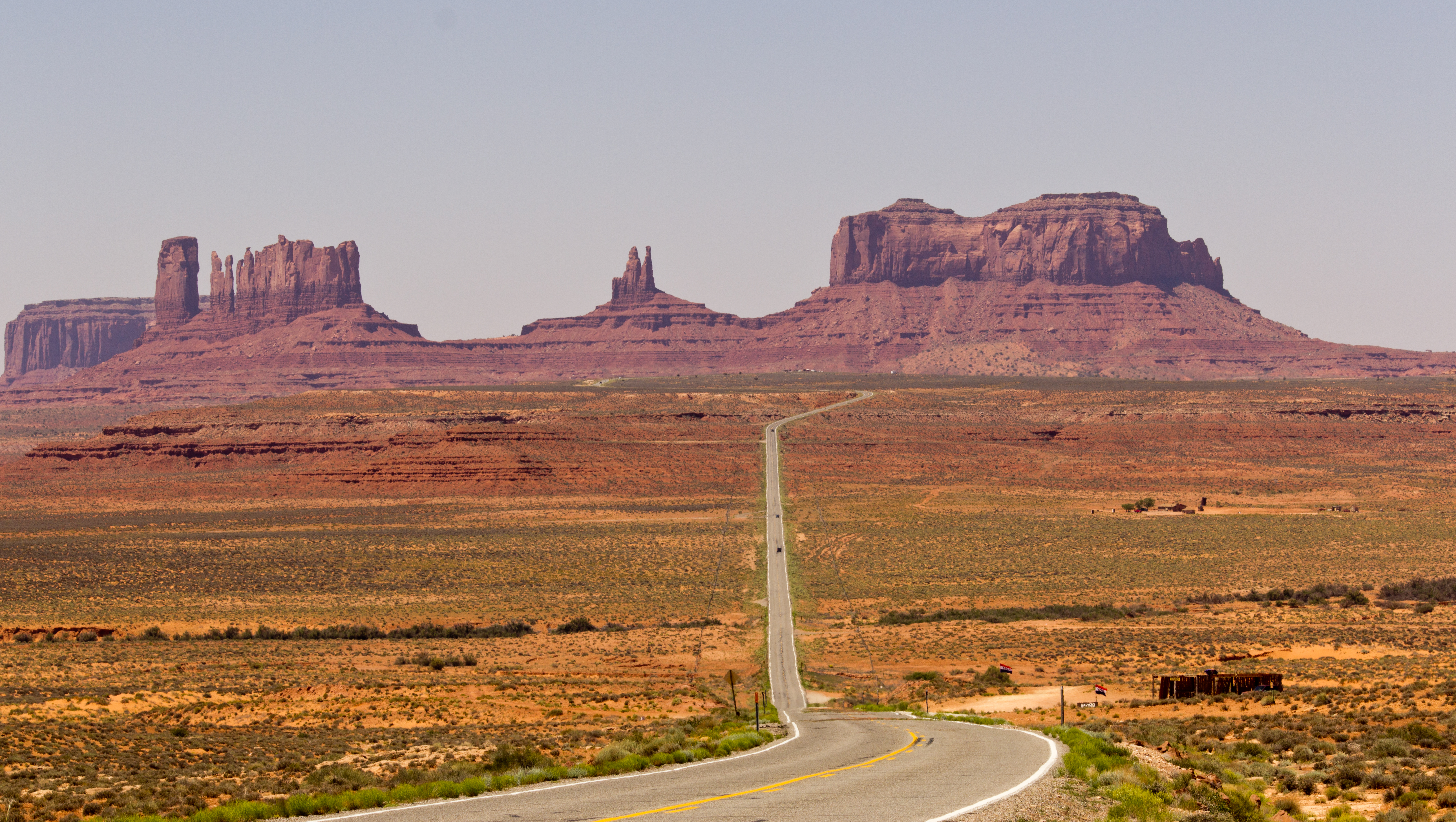 A long desert highway leading toward the monumental mesas of the American Southwest
