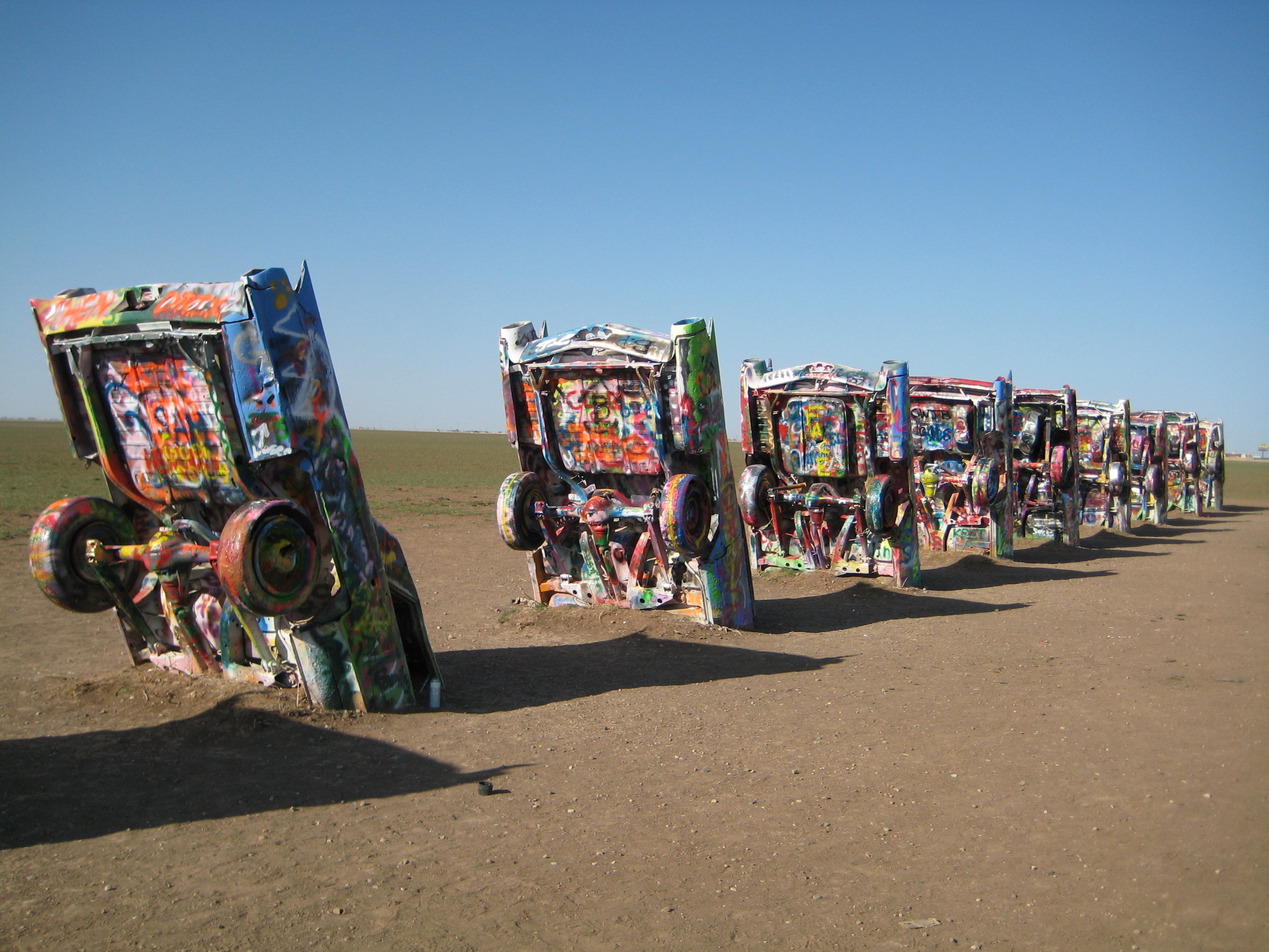 A long row of brightly painted Cadillacs rises from the open Texas Panhandle beside Route 66