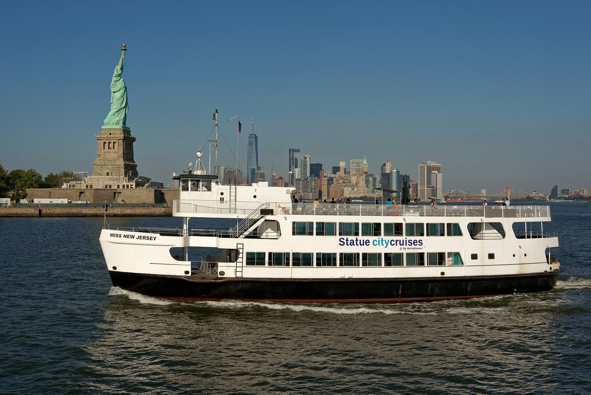 Statue City Cruises ferry passing Liberty Island with Lower Manhattan beyond