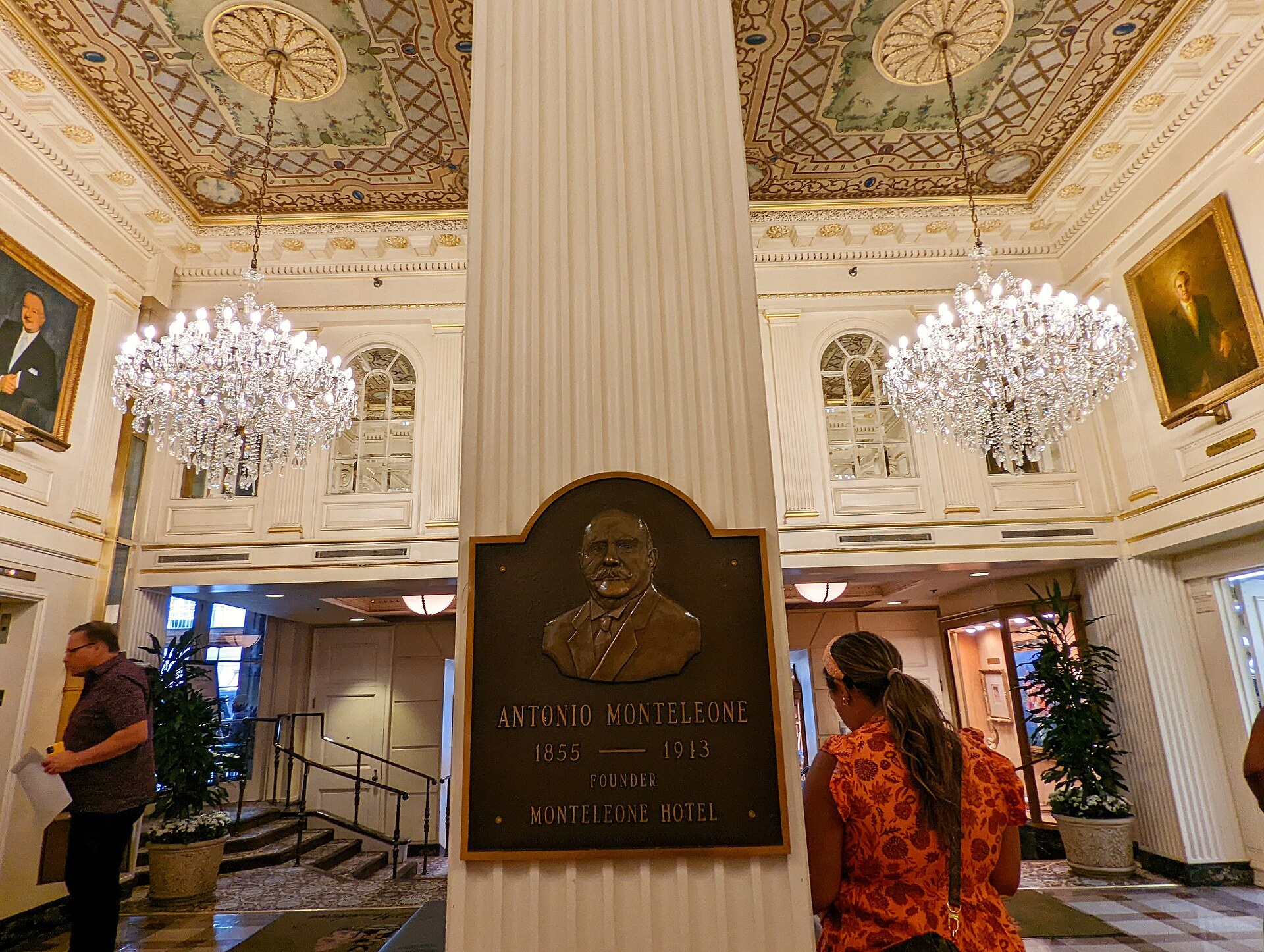 Travelers beneath chandeliers in the ornate lobby of historic Hotel Monteleone on Royal Street