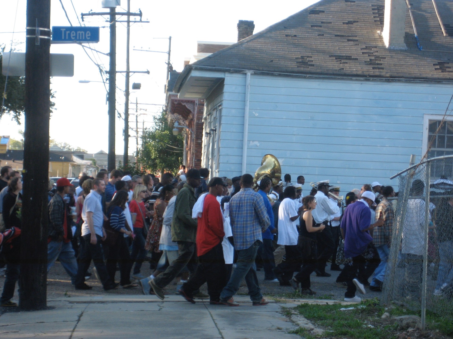 A Tremé second line procession with brass musicians and neighbors moving through the street
