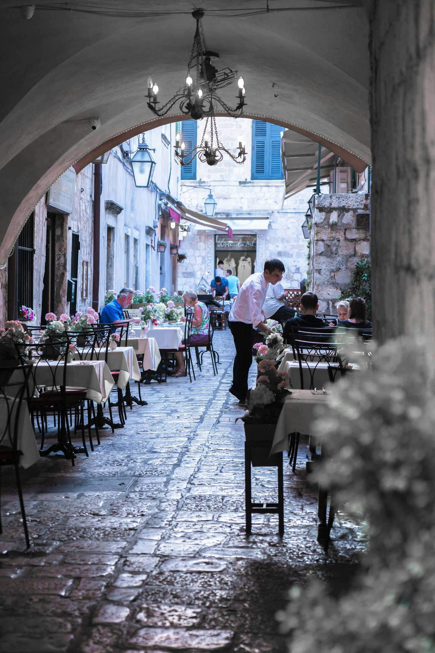 Diners and a waiter in a narrow restaurant passage in Dubrovnik's old town