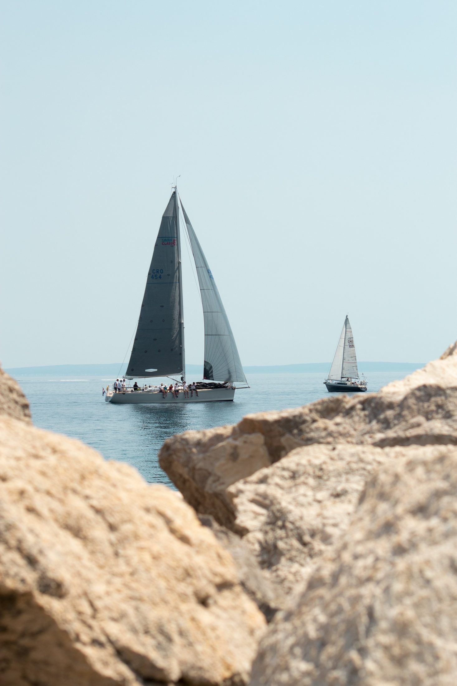 Two Croatian sailboats crossing the Adriatic beside a rocky coast