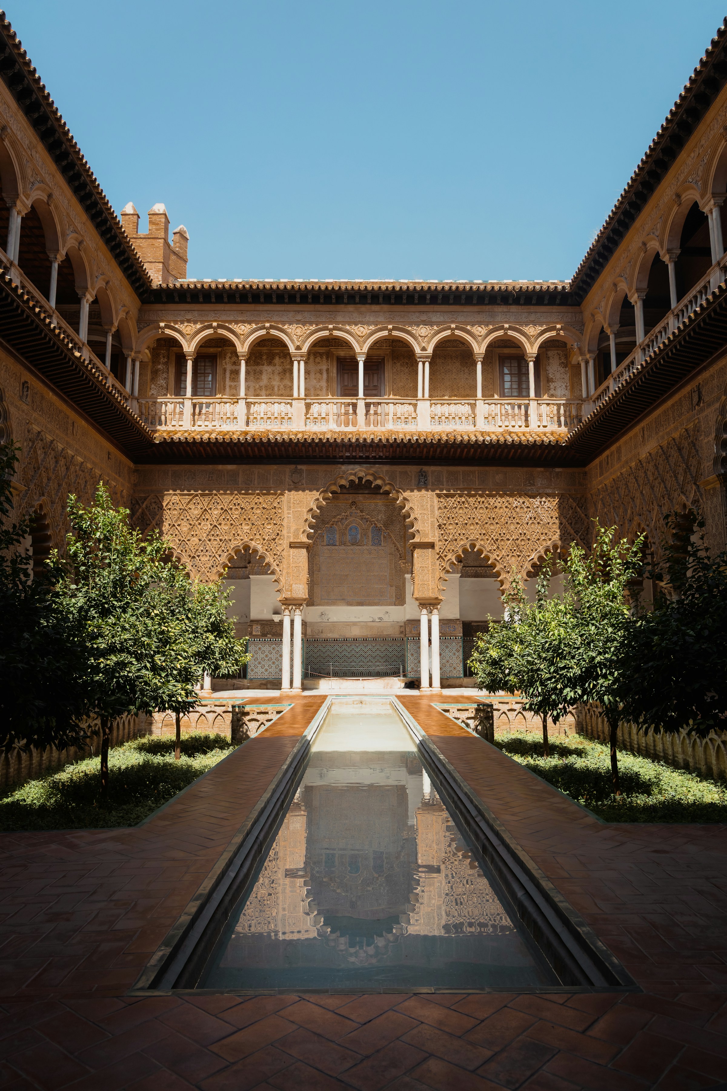 Ornate arches and a reflecting pool in a sunlit Seville courtyard