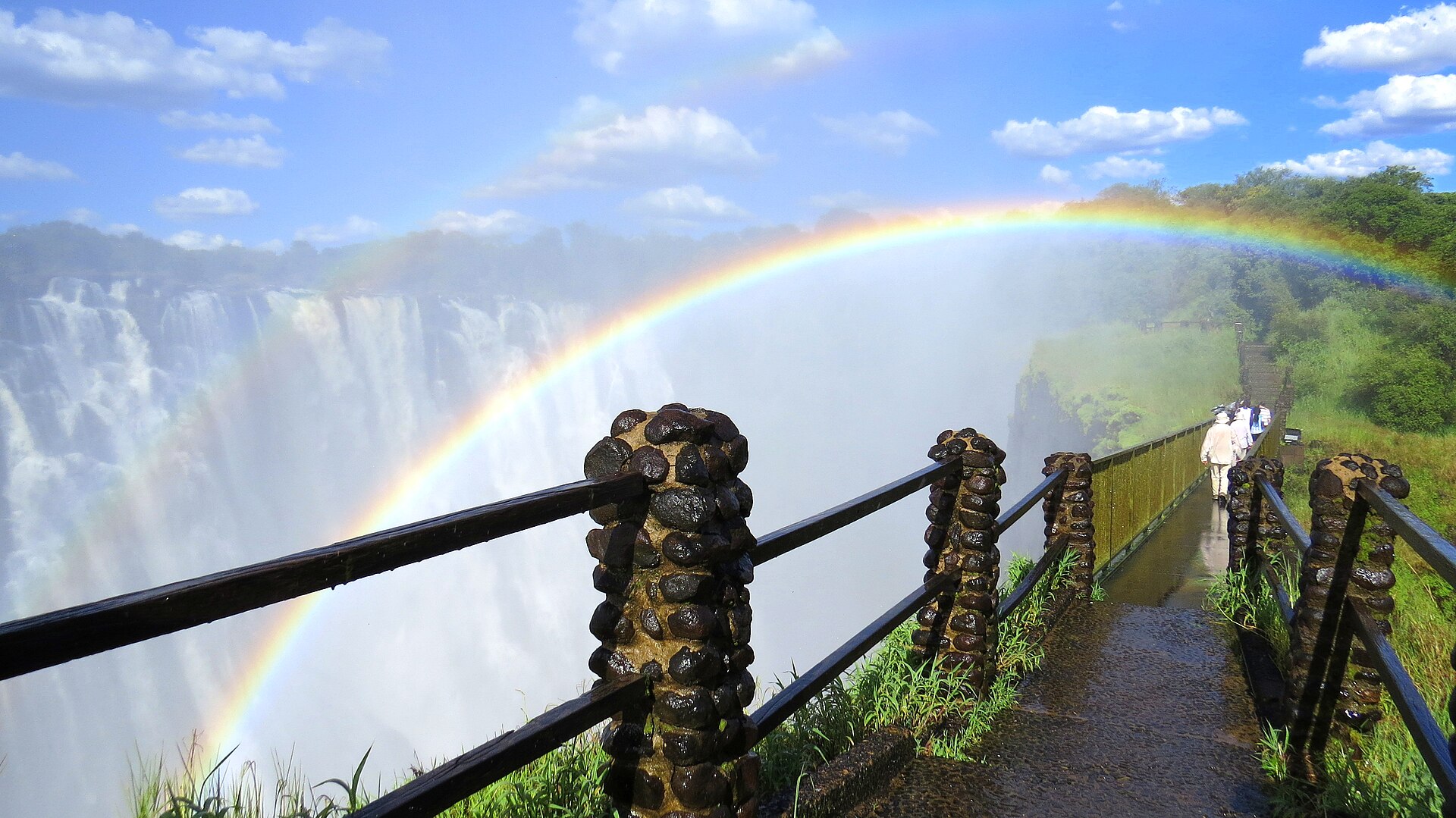 A rainbow spanning Victoria Falls beside the Zambian rainforest footpath