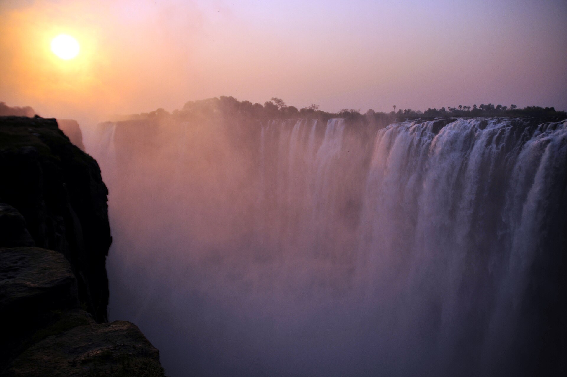 Victoria Falls spanning the basalt gorge beneath warm evening light on the Zimbabwe side